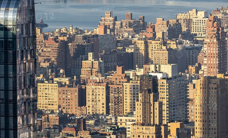 From above, an expansive view of countless high-rise buildings and intricate architecture layers in downtown New York City, showcasing a bustling urban landscape illuminated by afternoon sunlight