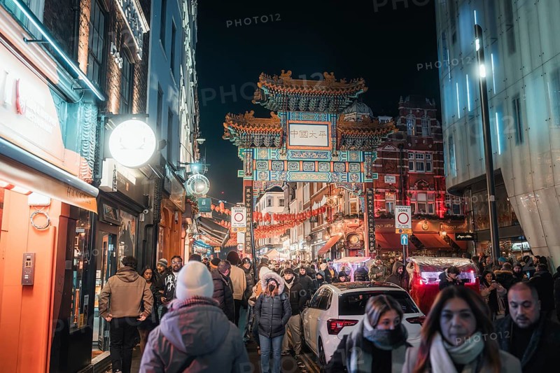 People stroll through Chinatown past an illuminated archway, New Year's Eve London, United Kingdom