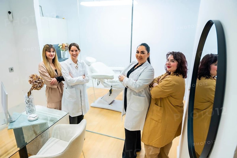 Four confident women, doctors and staff, standing with arms crossed in a modern aesthetic center or medical spa, ready to provide skincare and beauty treatments