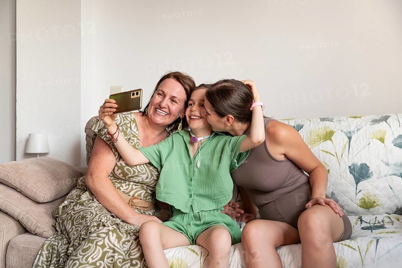 A heartwarming scene of a family with a disabled girl with a tracheostomy, sharing a joyful moment. The girl smiles brightly as they take a selfie, capturing the love and happiness they share