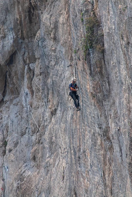 Worker climbing on a rock wall on the island of Capri, Campania, Italy