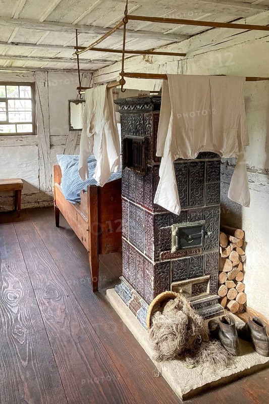 Historic dormitory with tiled stove at the back single bed for one person in old rebuilt restored day labourer's house half-timbered house in open-air museum Neuhausen, Neuhausen ob Eck, district Tuttlingen, Baden-Württemberg, Germany