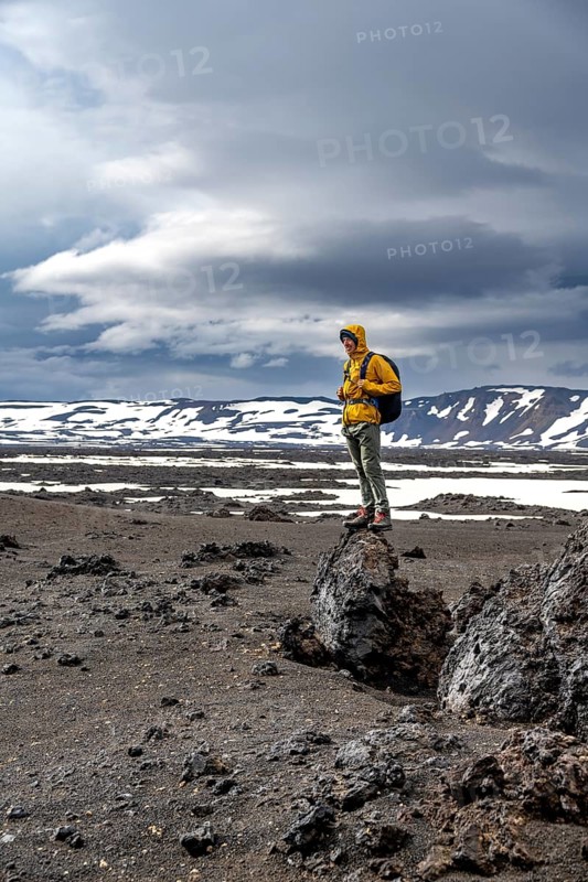 Hikers in snow-covered volcanic landscape with volcanic sand and petrified lava, crater of Askja volcano, Icelandic highlands, Iceland