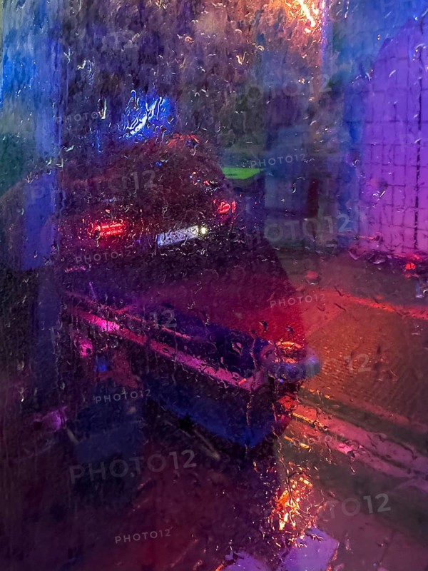 Car in car wash, blurred view through wet window pane