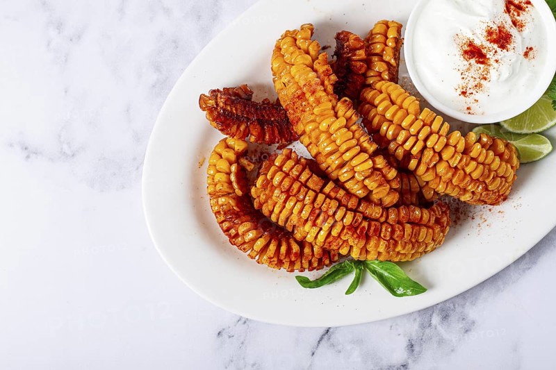 Corn ribs, with cream sauce, spices and lime, appetizer, on a white plate, homemade, no people