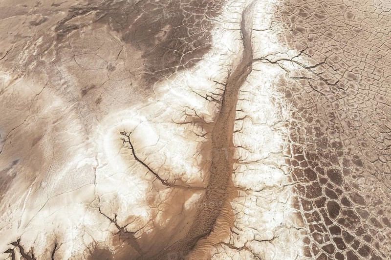 Aerial view of a barren, cracked landscape showcasing intricate patterns of dried earth. The arid terrain emphasizes the effects of a dry climate on the environment