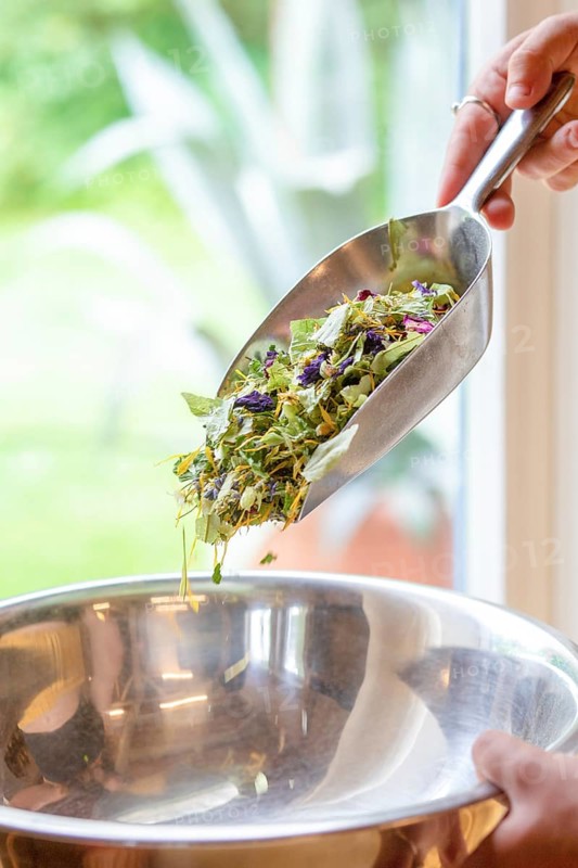 A vibrant blend of natural ingredients for anti-stress and digestive tea, featuring dried mallow flowers, roses, lemon balm leaves, and lemon verbena in a laboratory setting