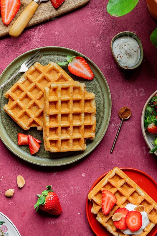 Delicious homemade waffles topped with strawberries and yoghurt on a rustic plate. A cozy and romantic setting perfect for a sweet breakfast or dessert moment