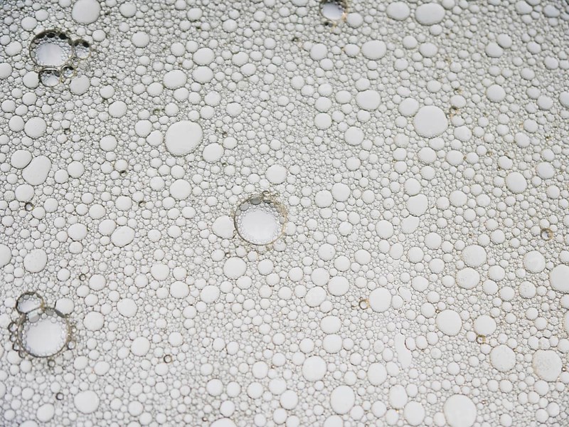 An abstract pattern featuring numerous bubbles in varying sizes, creating a distorted visual effect. The spherical shapes appear in a random, fluid arrangement