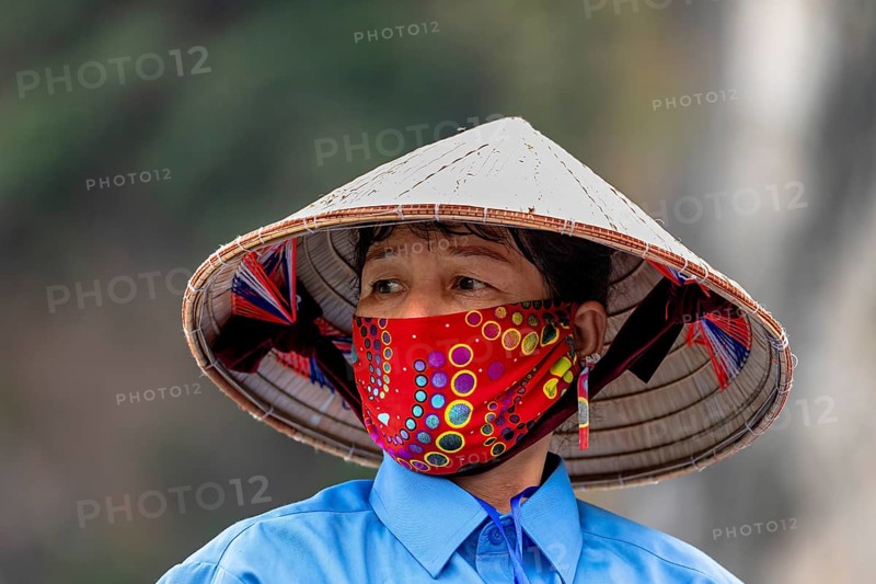 Woman with traditional hat and colourful face mask in natural environment, Vietnamese with straw hat in Halong Bay in Vietnam