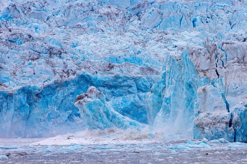 Ice chunk breaking from edge of calving Kongsbreen, marine-terminating glacier debouching into Kongsfjorden in summer, Svalbard / Spitsbergen, Norway