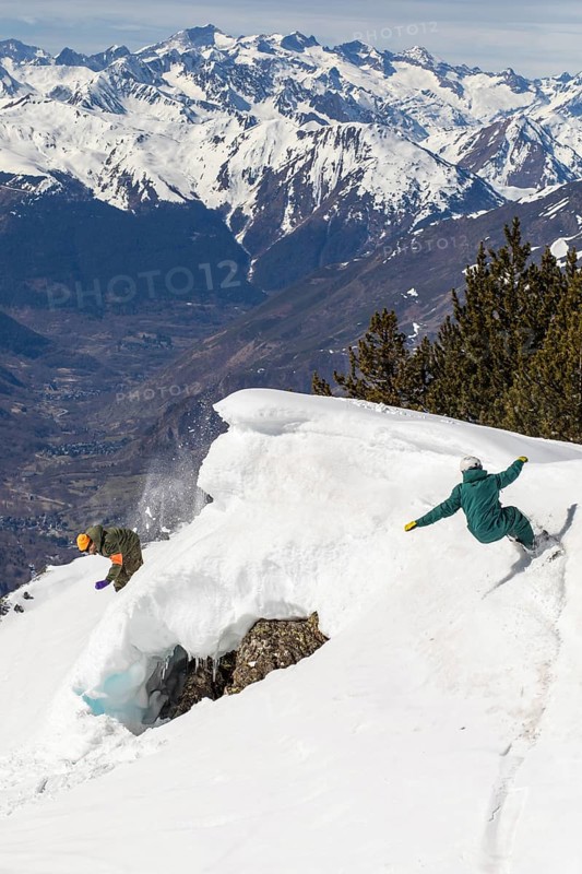 Two snowboarders skillfully navigate a steep, snowy mountain slope, enjoying the thrill and challenge of the descent in a pristine winter landscape with clear blue skies