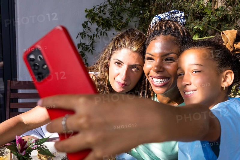 Joyful moment of a lesbian couple with their child, capturing a selfie outdoors. Embracing diversity, love, and family unity, highlighting pride and identity