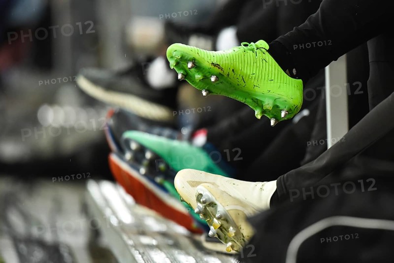 Professional football studded boots of players sitting on the bench