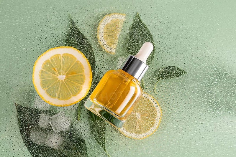 A vibrant skincare scene with a cosmetic of citrus serum placed alongside fresh lemon slices and a dewy green backdrop, symbolizing freshness and natural beauty
