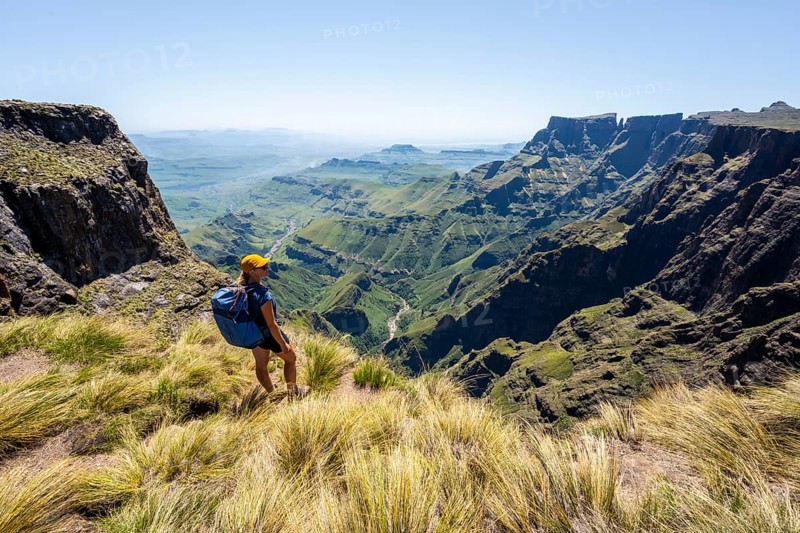Young hiker looking at the impressive mountains and cliffs of the Drakensberg Mountains, hiking trail on the Sentinel Hiking Trail, Drakensberg, KwaZulu-Natal, South Africa