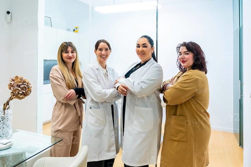 Group of diverse women standing together, posing with arms crossed, and smiling at an aesthetic center, representing professionalism and collaboration in the beauty and wellness industry
