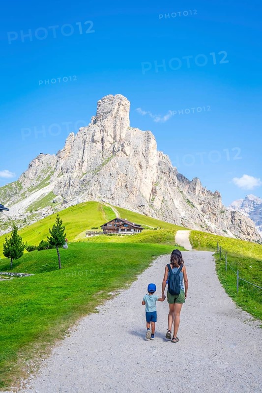 Mother and son walking near a mountain shelter, enjoying summer vacation in the italian alps