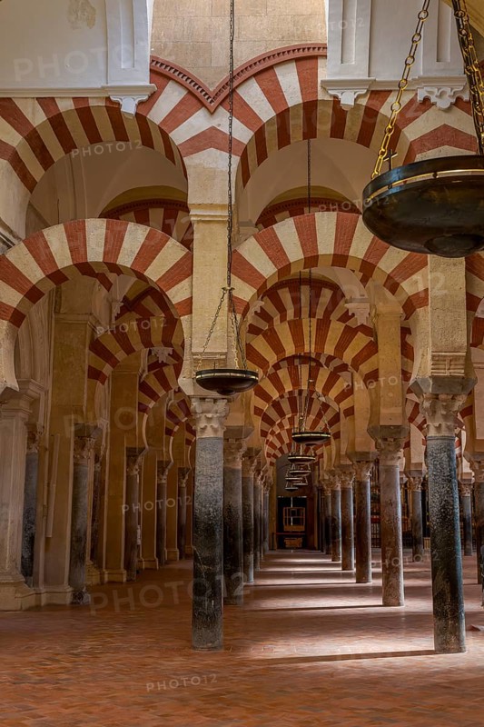 Seemingly endless row of Moorish arches with hanging lamps in the cathedral mosque of Córdoba (Mezquita-Catedral), Cordoba, Andalusia, Spain