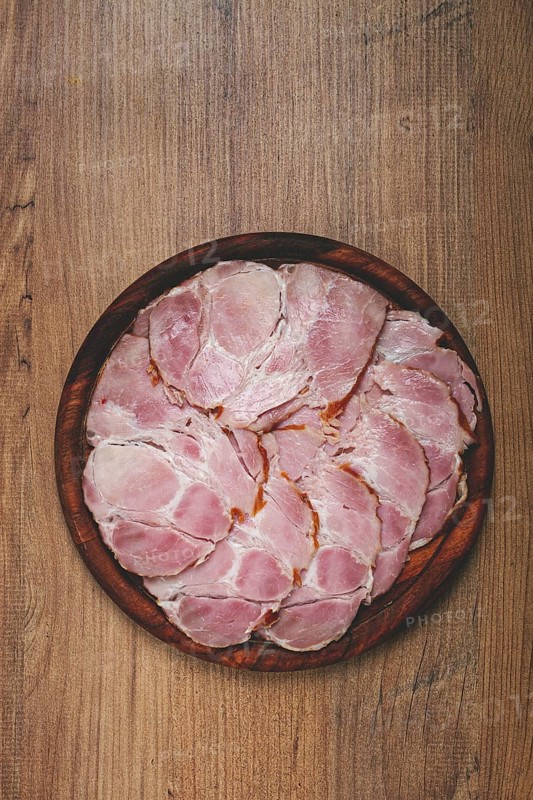 Sliced pork neck, boiled and smoked, smoked pork neck, sliced, on a wooden chopping board, close-up