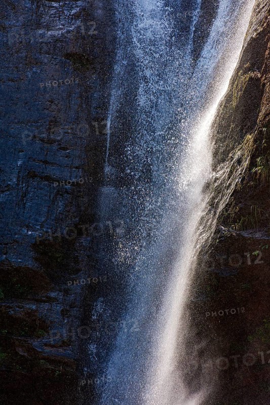 Water from a waterfall splashing between the rocks, illuminated by the sun in Minas Gerais, Minas Gerais, Brazil