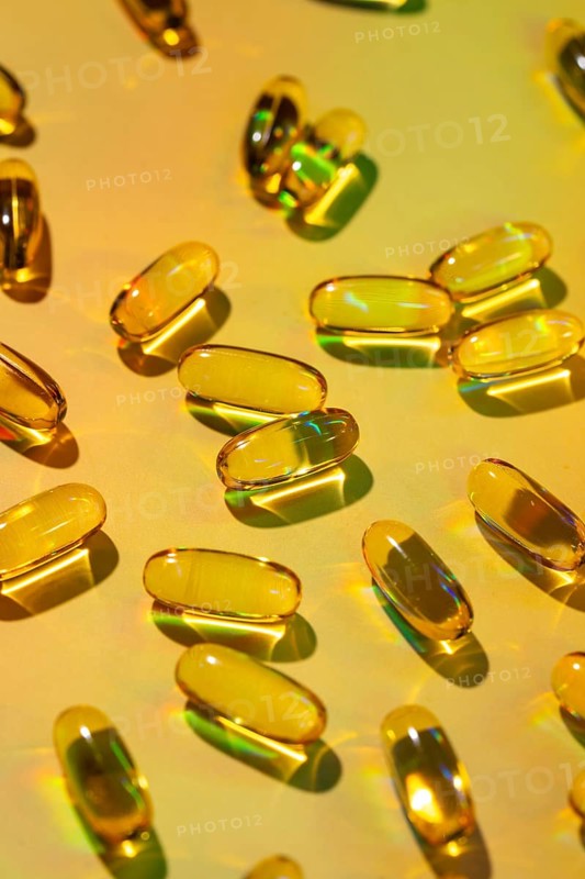 A vibrant image of translucent softgel capsules scattered across a colorful surface, symbolizing vitality and wellness. These vitamin supplements are key to a healthy lifestyle