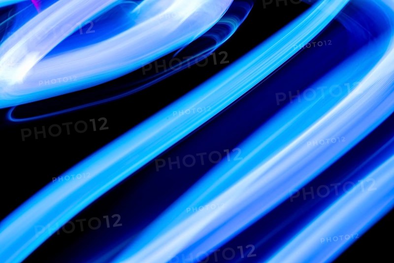 An abstract image showcasing dynamic blue light trails against a dark background. The motion blur creates a sense of movement and energy, enhancing the vibrant neon effect