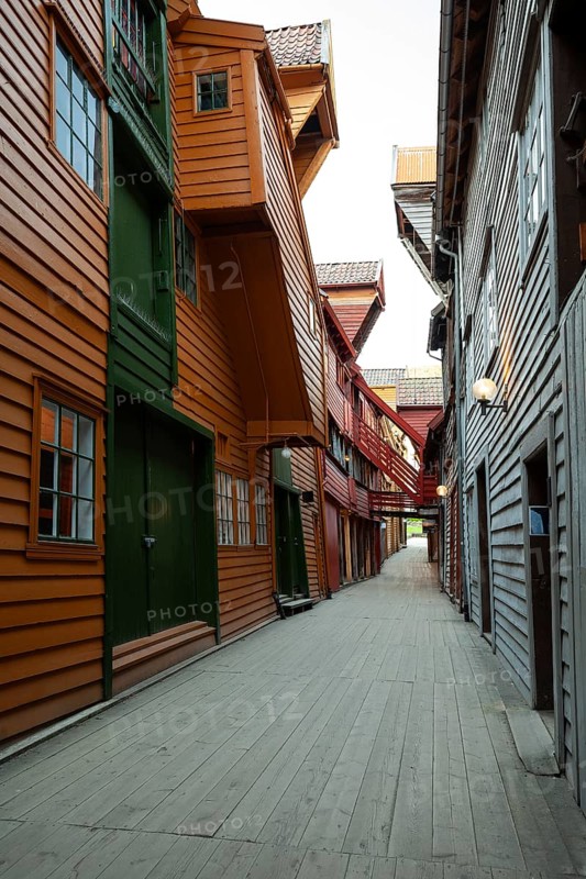 Summer day exploring behind facades in Bryggen Bergen, narrow lanes, colorful wooden buildings, historic trade stores, Vestland, Norway