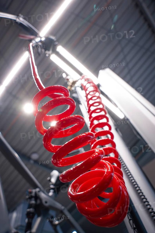 Red spiral cable in front of an illuminated ceiling in a workshop from an unusual angle, Waldbike Manufaktur, bicycle workshop, Calw, district of Calw, Black Forest, Germany