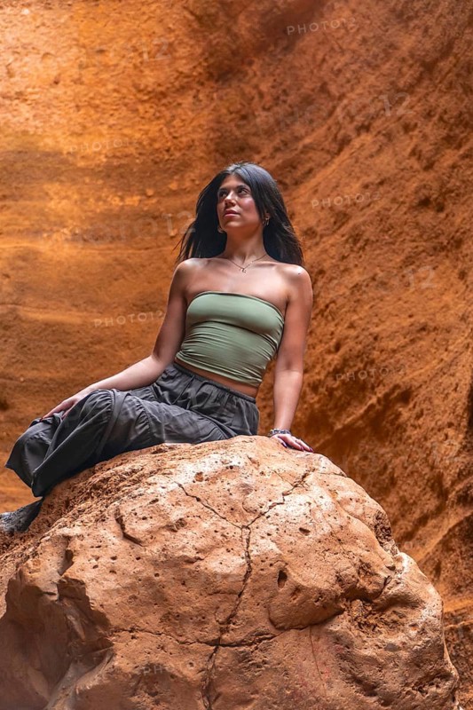 Young woman sitting on a rock, admiring the unique geological formations of barranco de las vacas in gran canaria, spain