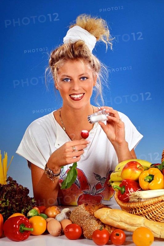 Blonde woman eating a radish for breakfast, fruit and vegetable basket, fruit, vegetables, 25 years, salt shaker, salt studio shot, Lower Saxony, Federal Republic of Germany