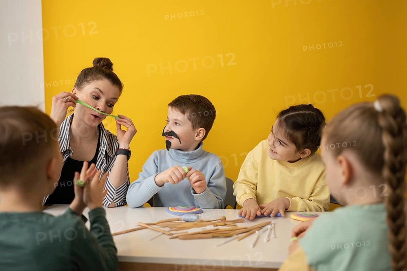 A fun, creative learning session with children engaging in arts and crafts. A teacher and kids enjoy playful activities, fostering imagination and creativity in a bright setting