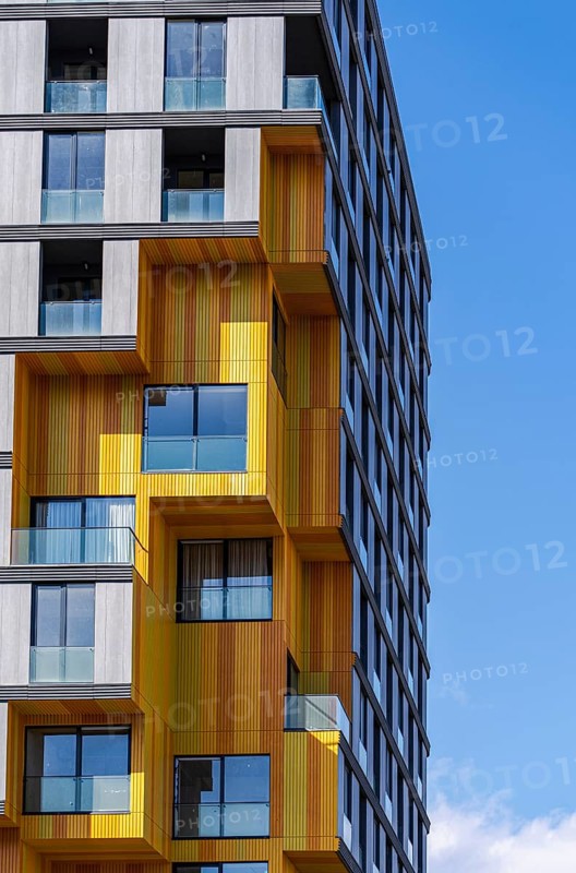 This image captures the intricate blend of materials in modern architecture, highlighting glass, concrete, and metal elements in a vibrant suburban building