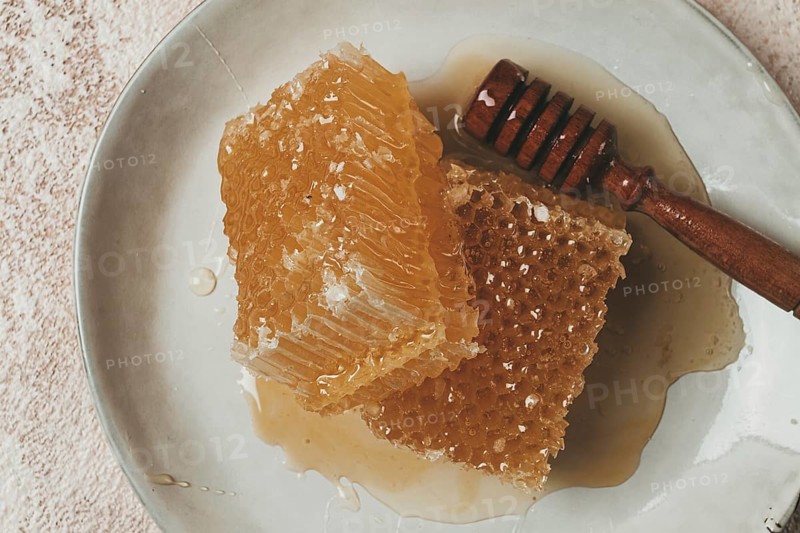 Honeycomb, with a wooden spoon-spindle, on a plate, no people