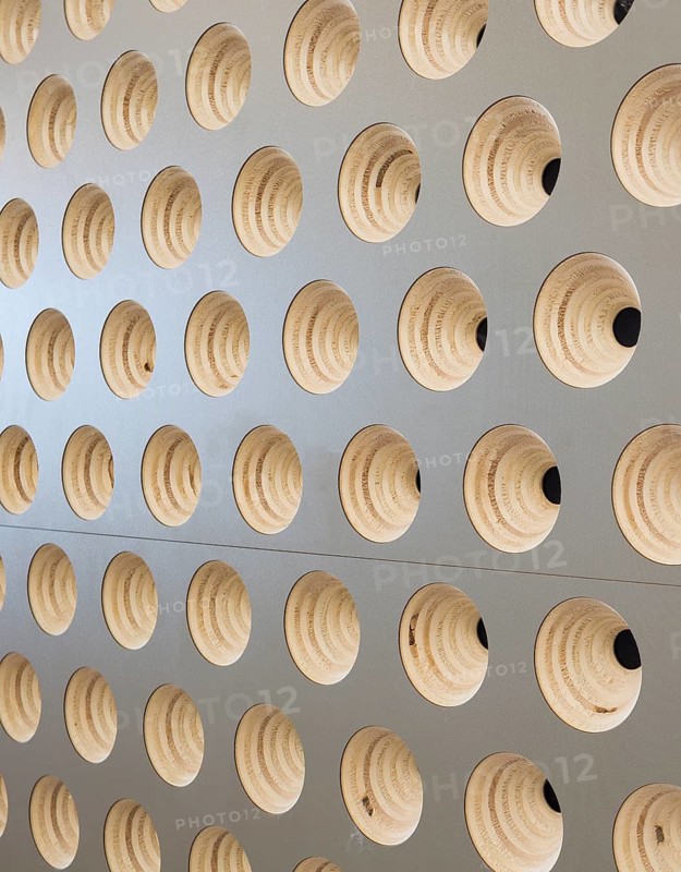 A close up view of a club wall featuring circular, wooden patterns embedded in a light surface. The design creates a visually appealing and modern geometric texture
