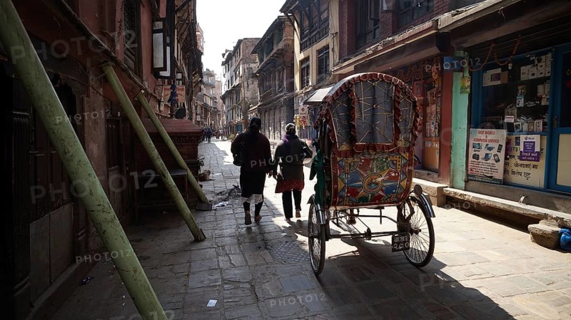 Two people with a rickshaw in a shady alley in Kathmandu, houses are secured and supported shortly after the earthquake in Kathmandu, Nepal
