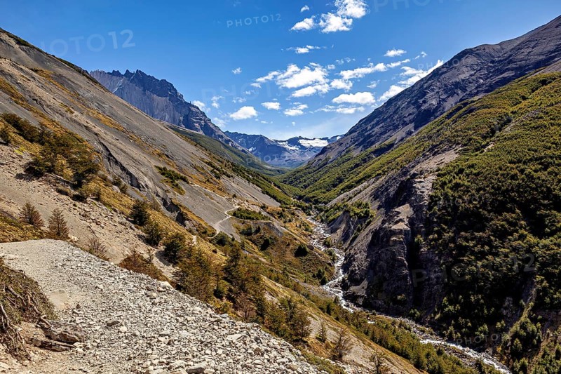 View of a valley between steep mountains, crossed by a river under a cloudy sky, The landscape of the Torres del Paine National Park in Patagonia Chile