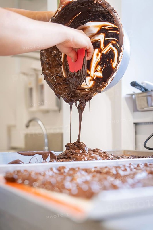 Liquid chocolate is poured from a bowl onto a work surface, Burch Schokolade production, Haselstaller Hof, Gechingen, Germany