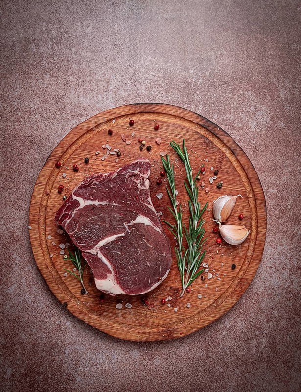 Fresh raw rib eye steak, on a cutting board, top view