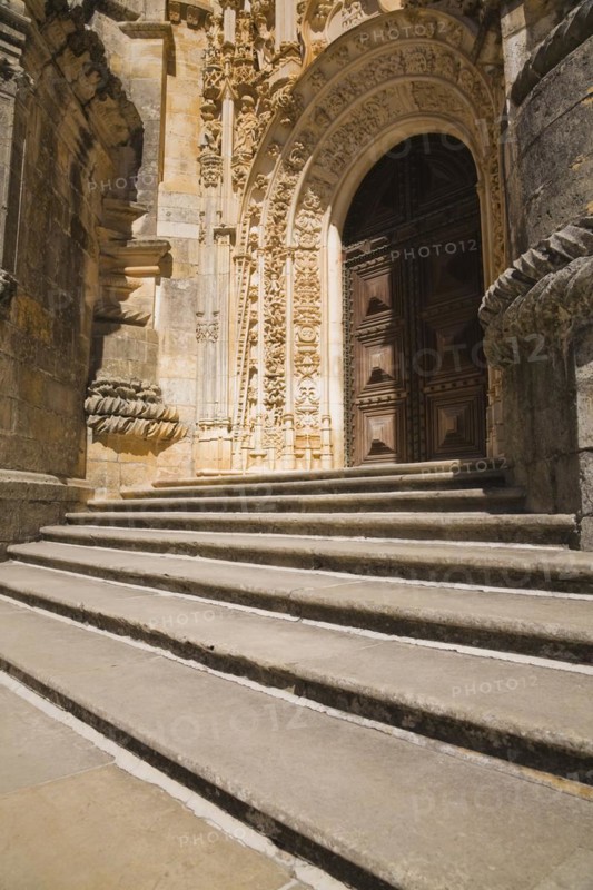Steps and arched entrance door decorated with architectural details at the Convent of Christ in Tomar, Portugal