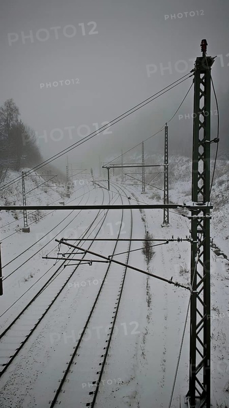 Snow-covered railroad tracks lead into the foggy distance, Rennsteig, Frankenwald nature park Park