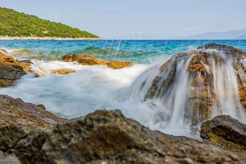 Wellen brechen an einem Felsen im Meer an einem sonnigen Tag auf der Insel Cres, Kroatien