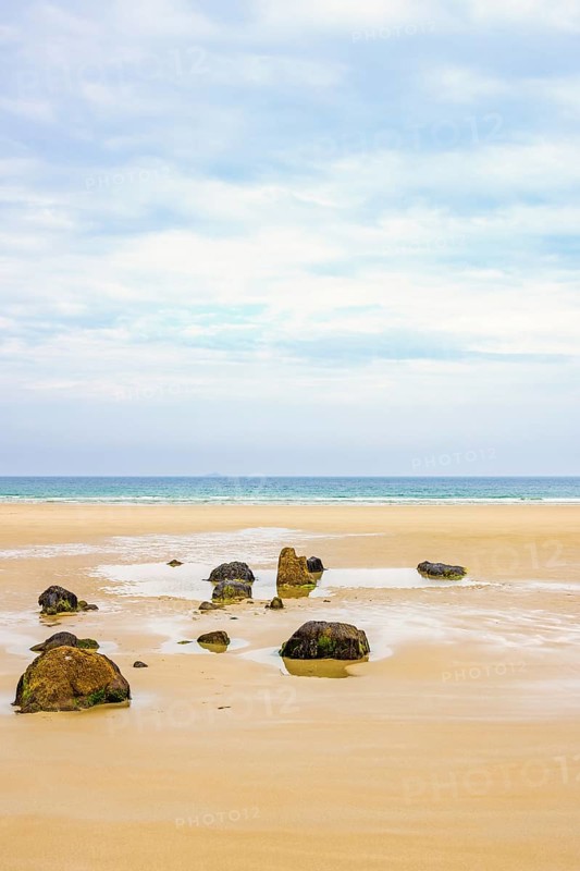 Boulders on a empty sand beach with a seascape view to the horizon a sunny summer day, Crozon peninsula, Bretagne, France