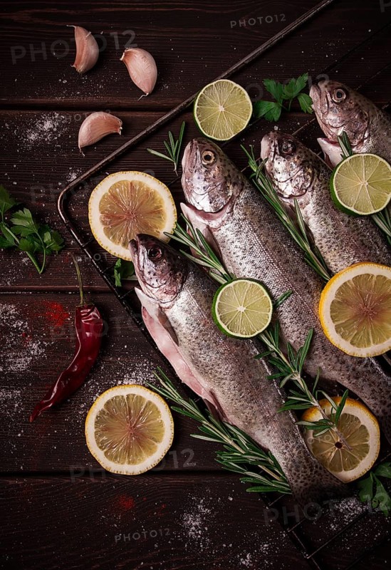 Raw rainbow trout, with lemon and herbs, on a wooden table, no people