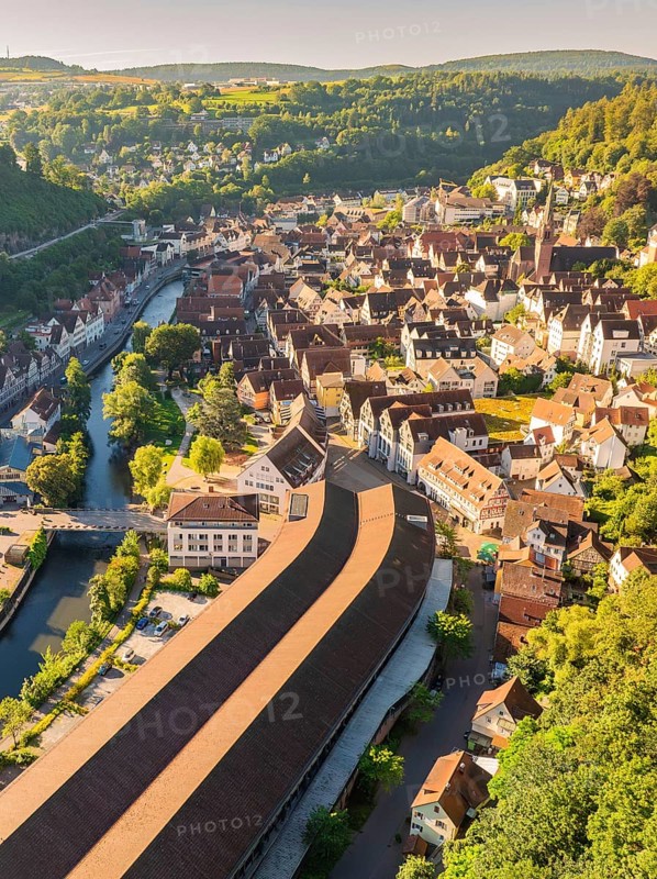 Aerial view of a town with many roofs and a river and bridge, surrounded by green hills and historic architecture in summer, Calw, Black Forest, Germany