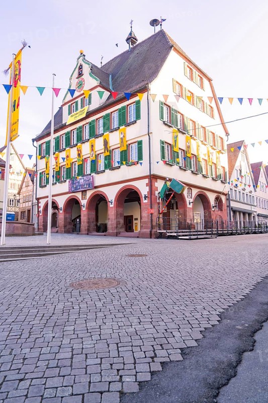Historic half-timbered house on the market square with strong green shops and colourful flags along the cobblestone street, Fasnet, Weil der Stadt, Böblingen district, Germany
