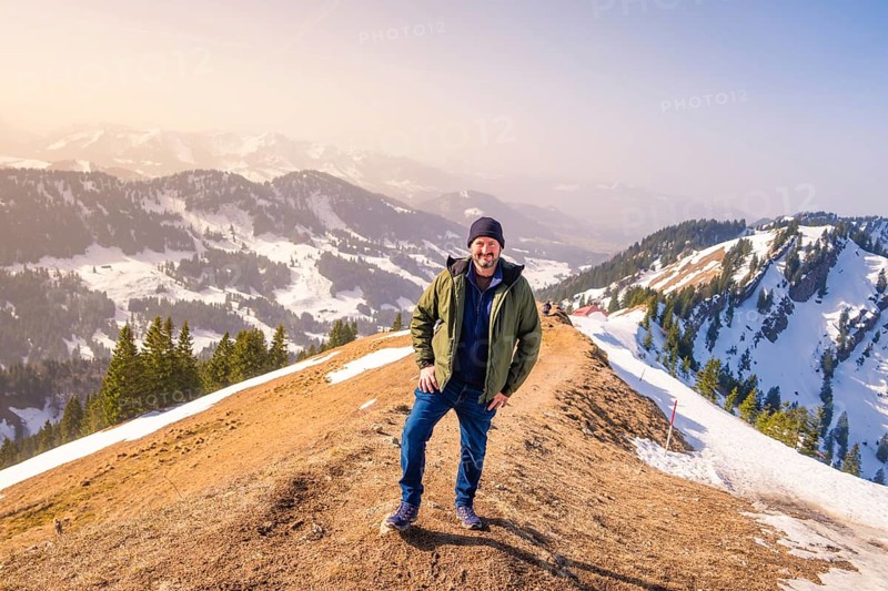 Person standing on a mountain under a clear sky with a view of the snowy landscape, Hochgrat Mountains, Allgäu Alps, Oberreute, Germany