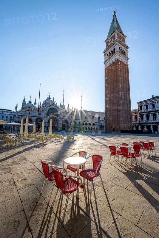Chairs and tables of cafes, St Mark's Square in the morning light, St Mark's Basilica and Campanile, Sun Star, Venice, Veneto, Italy