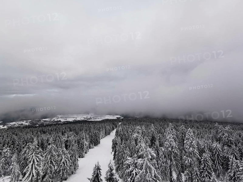 View from above of snow-covered forest landscape that disappears in a haze of fog, hiking in the Fichtelgebirge nature park Park