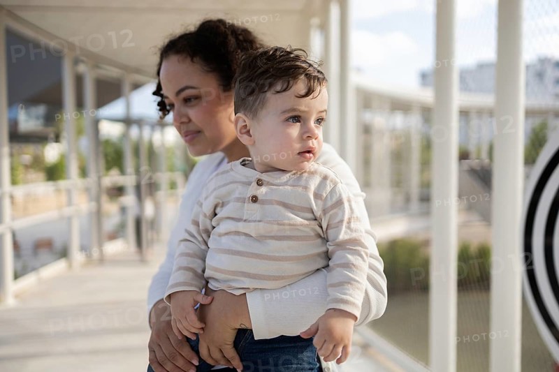A warm moment captured as a mother holds her baby in a serene park setting. The bond between them is evident, highlighting a loving connection and peaceful surroundings